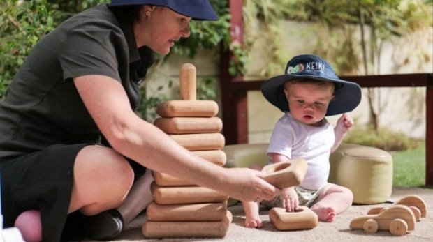 Baby-and-educator-using-natural-blocks-outdoors-700x467