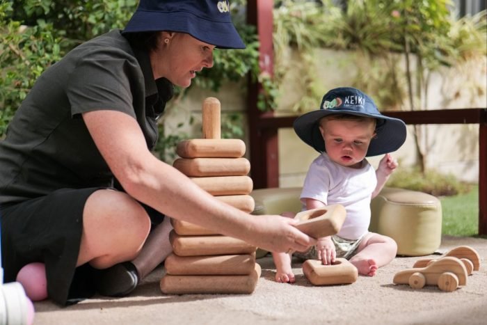 Baby-and-educator-using-natural-blocks-outdoors-700x467
